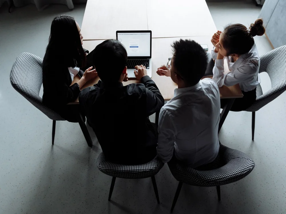 Four colleagues working around a laptop
