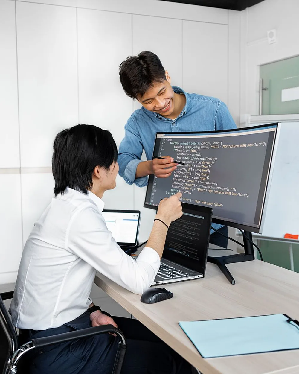 Two young professionals working together at computers in a modern office