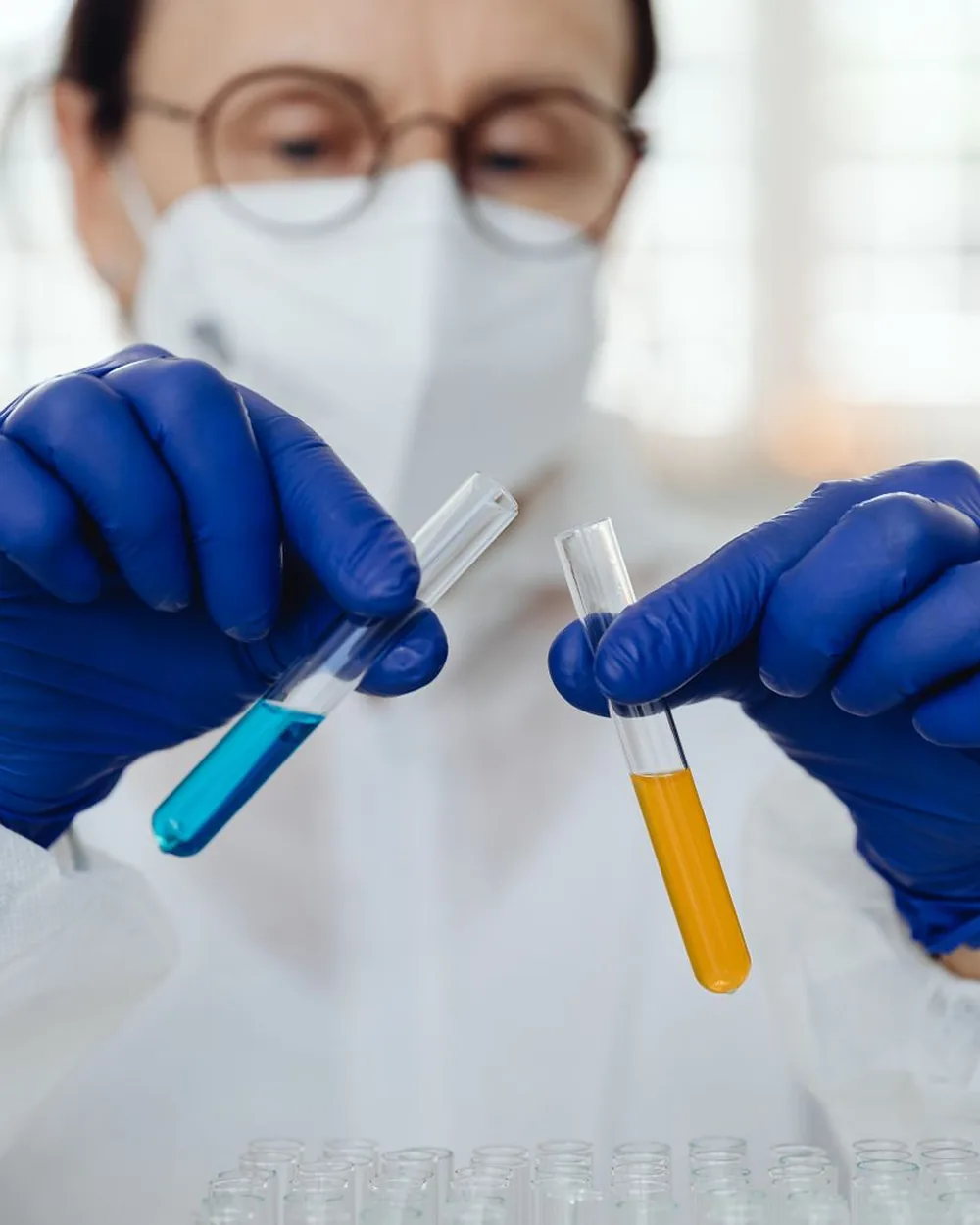 A scientist in gloves holding up two test tubes