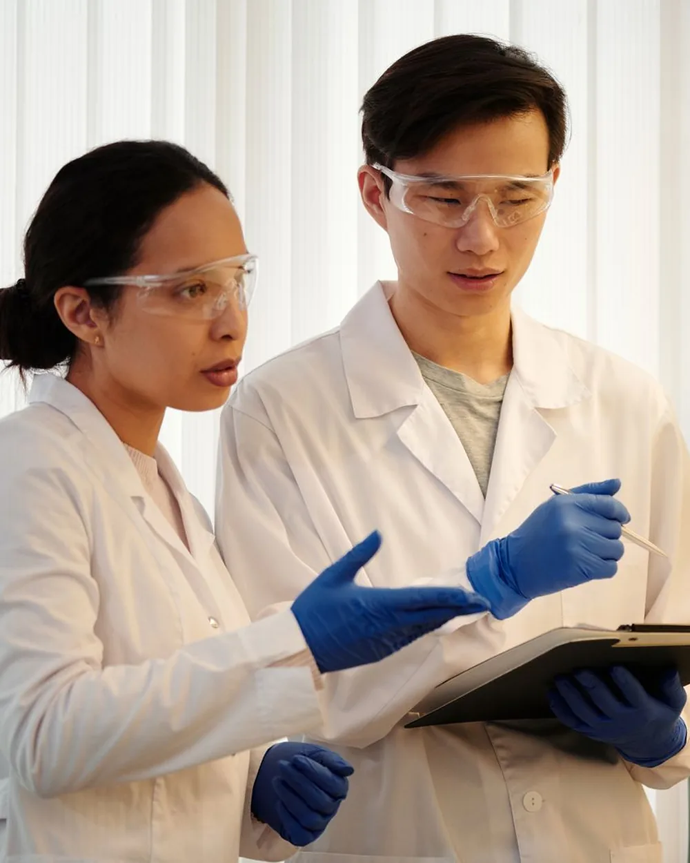 Two researchers in gloves talking over their work in a laboratory
